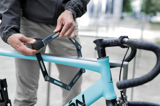 person locking blue bike to rack with ABUS Bordo 5700