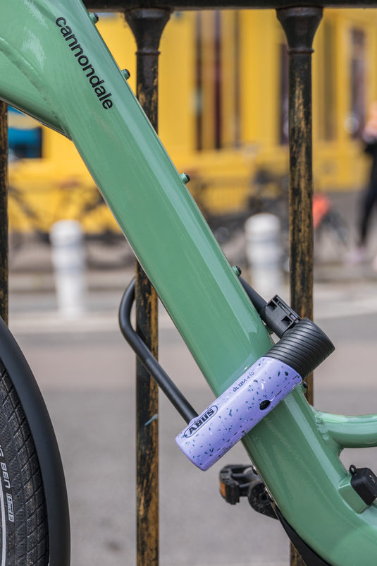 green biicycle secured to railing with purple ABUS Ultra 410K
