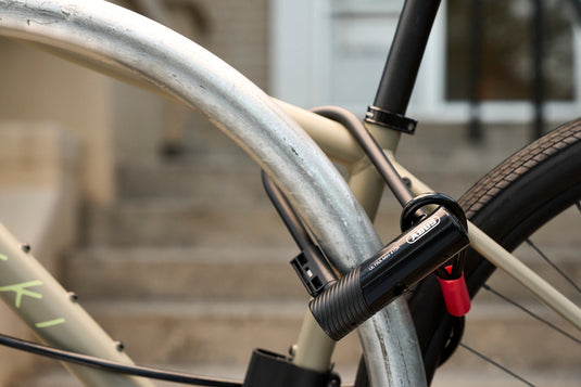 beige bicycle sercured to rack with black ABUS Ultra 410K Mini and cobra cable securing wheels
