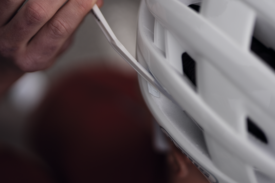Close-up of a person adjusting the chin strap of a white helmet.