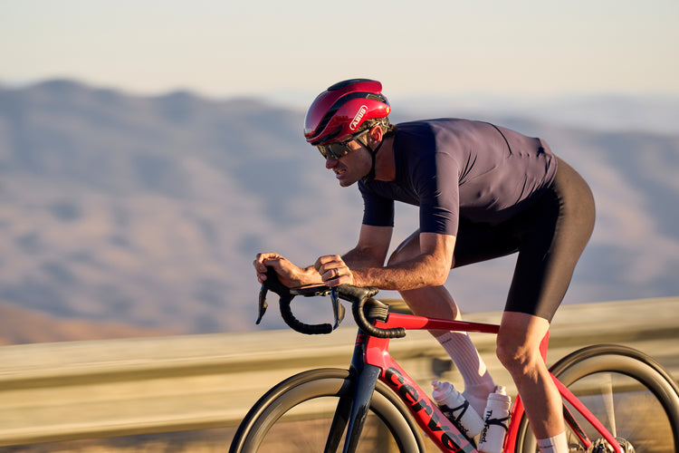 cyclist on red bike riding mountain road wearing red ABUS GameChanger 2.0 helmet