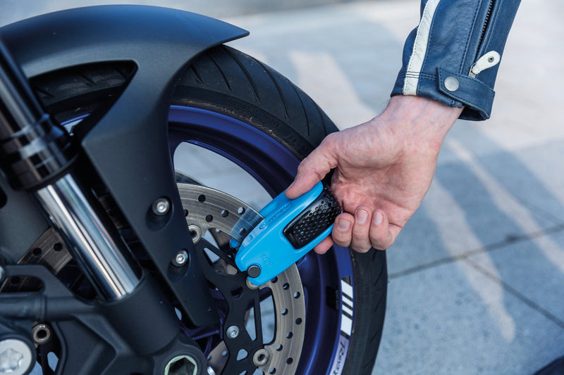 Load image into Gallery viewer, Hand using a blue lock on a motorcycle wheel #color_blue

