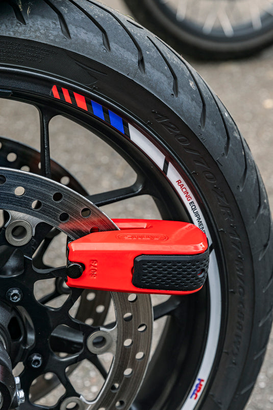 Close-up of a motorcycle wheel with a red lock on a blurred background