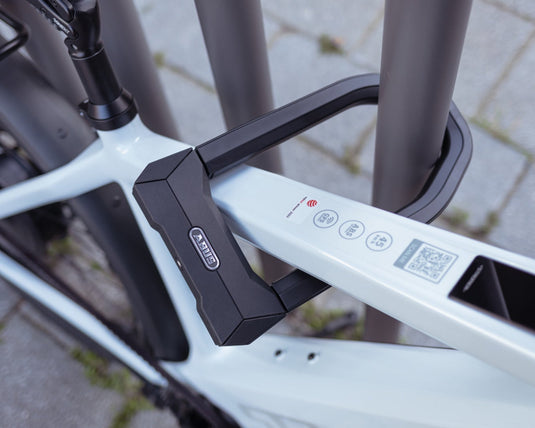 ABUS GRANIT Super Extreme 2500 u-lock securing white bike to railing #size_230mm