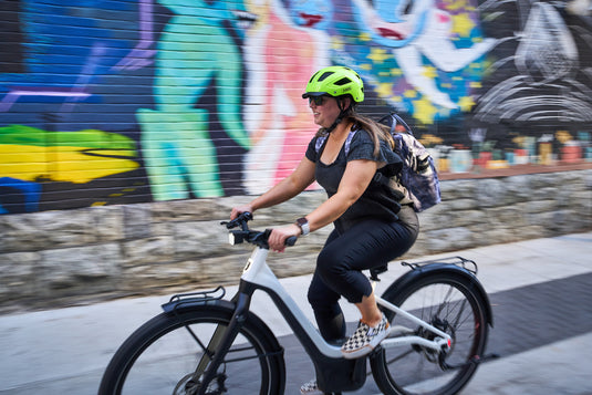 rider on white e-bike riding down road with colorful mural in back