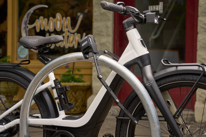 Load image into Gallery viewer, White electric bike with black accents parked outside a building locked with a Bordo 6000KA/120 #size_120cm
