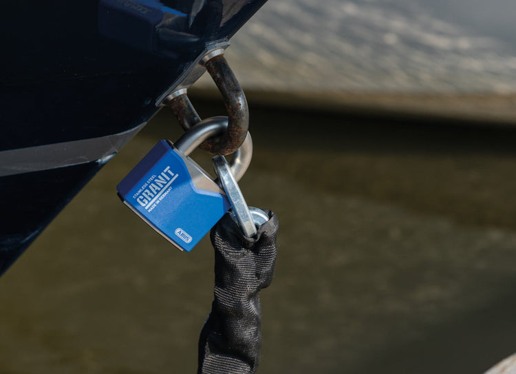 Close-up of a boat anchor with a Granit 37ST/55 padlock l on a dock.