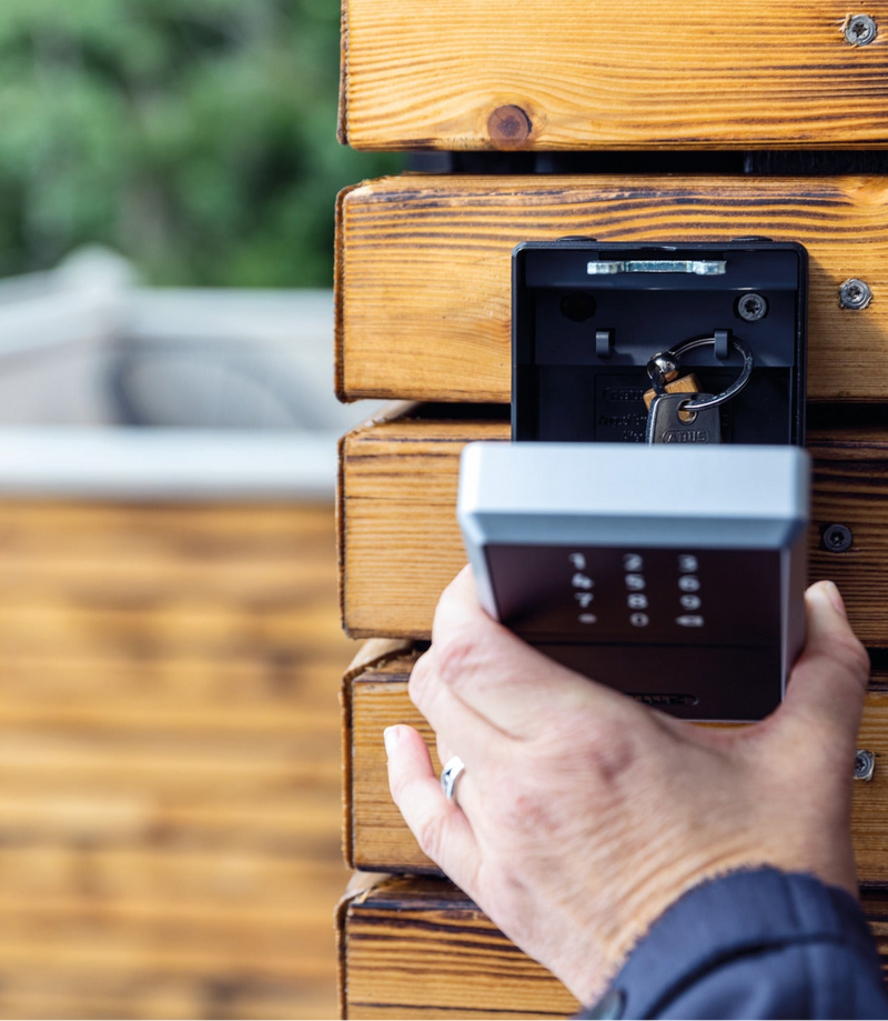 Load image into Gallery viewer, Hand opening a 787 KeyGarage bluetooth key box with a blurred background.

