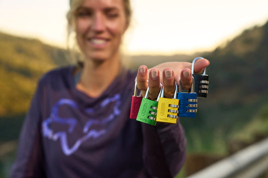 Person holding colorful combination locks with a blurred natural background