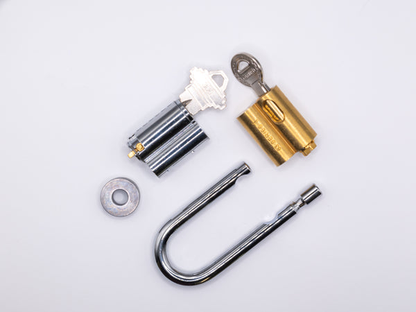 Locksmith tools including a shackle collar, shackle, and cylinder bible covers on a white background.