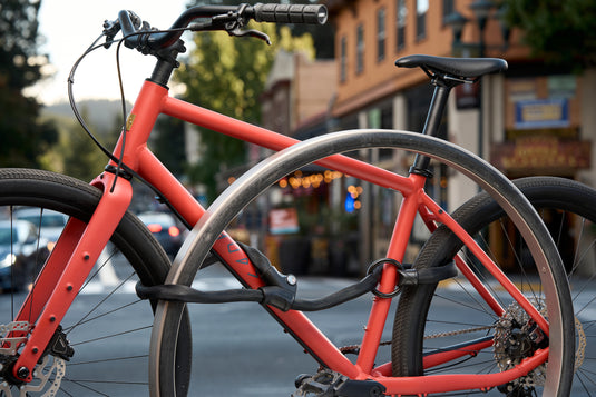 Infinity loop securing orange bicycle and wheels to rack in downtown setting